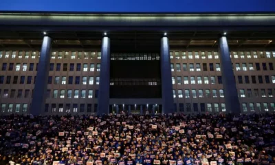 Protesters holding signs outside large building at night.