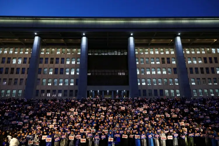 Protesters holding signs outside large building at night.