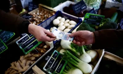 Exchanging money at a vegetable market stall.