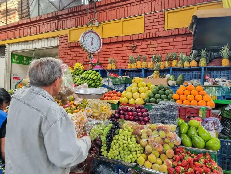 Person shopping at vibrant fruit market stall.