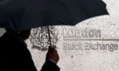 Silhouette with umbrella at London Stock Exchange entrance.