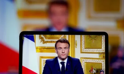 Person speaking on screen with French flag backdrop.