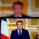 Person speaking on screen with French flag backdrop.