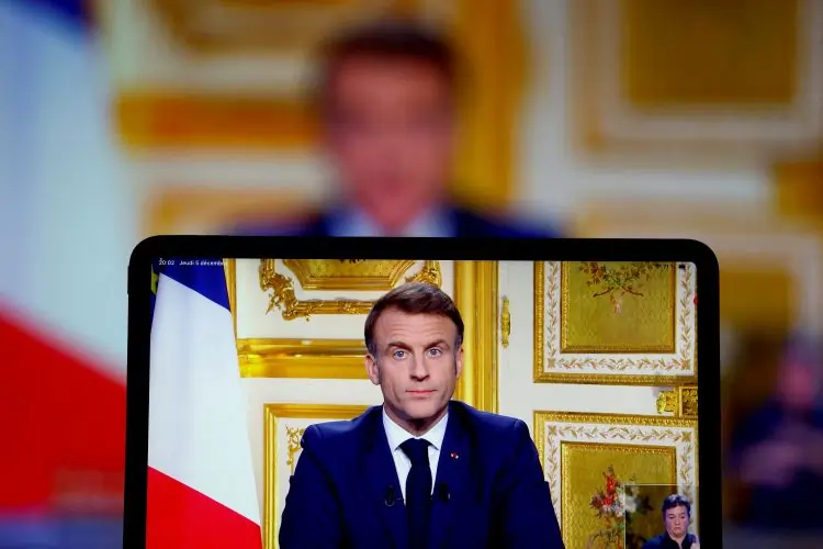 Person speaking on screen with French flag backdrop.