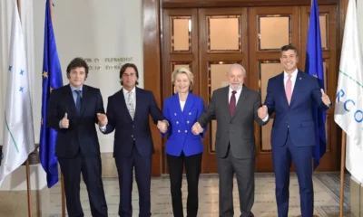 Group of five leaders holding hands indoors.