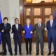 Group of five leaders holding hands indoors.