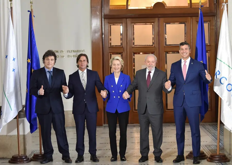 Group of five leaders holding hands indoors.