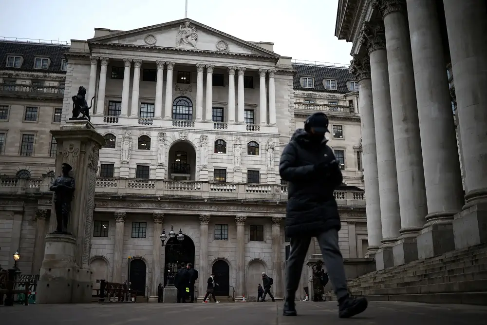 Person walks past historic building in winter attire.