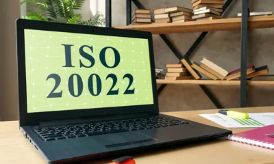 Laptop displaying ISO 20022, books in background.