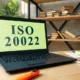 Laptop displaying ISO 20022, books in background.